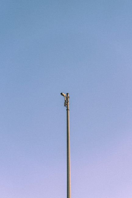 A CCTV camera mounted on a tall pole with a blue sky background in Dubai.